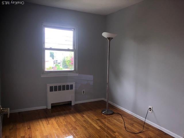 69 E 1st St, Freeport, NY 11520 - unfurnished room with radiator, wood finished floors, and baseboards