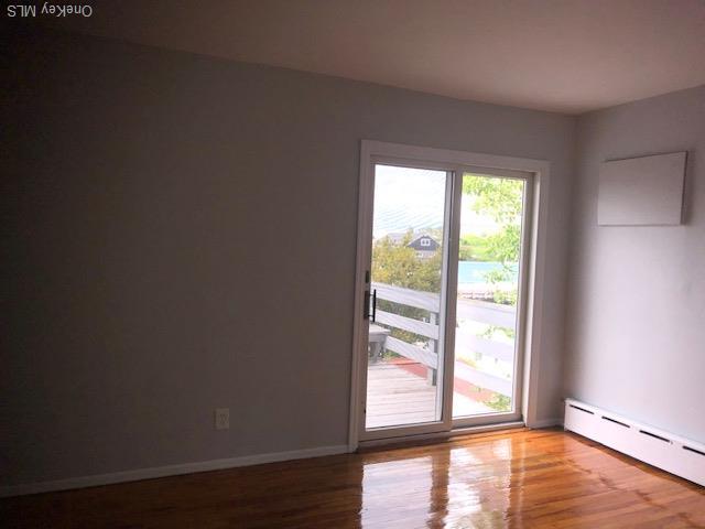 69 E 1st St, Freeport, NY 11520 - empty room with a baseboard radiator, wood finished floors, and baseboards