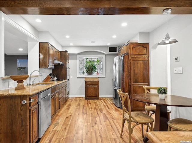 kitchen with sink, light hardwood / wood-style flooring, light stone countertops, appliances with stainless steel finishes, and decorative light fixtures