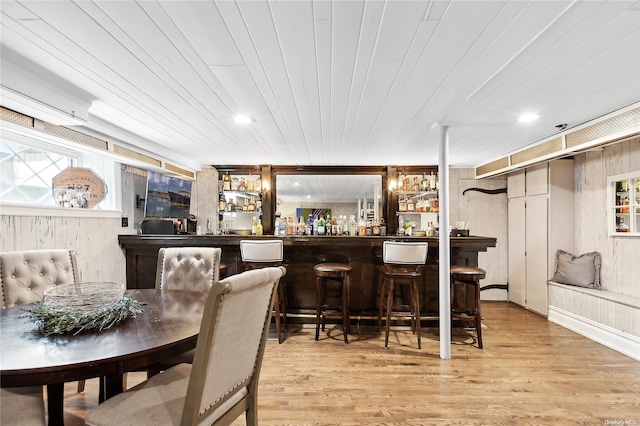 bar featuring plenty of natural light, light wood-type flooring, wooden walls, and wooden ceiling