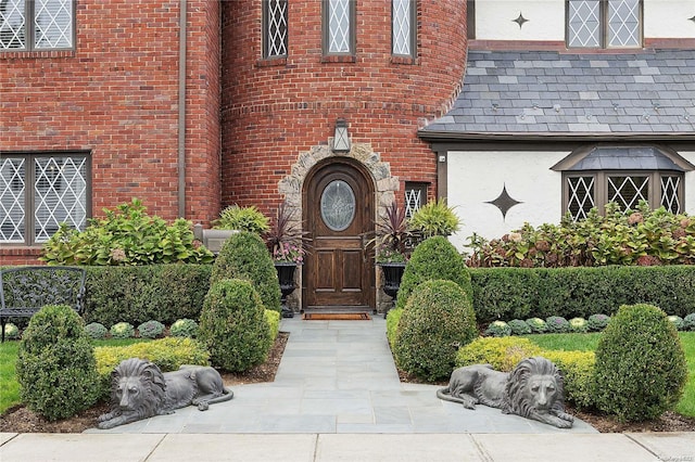 38 Royal Ct, Rockville Centre, NY 11570 - view of exterior entry featuring brick siding, stucco siding, and a high end roof