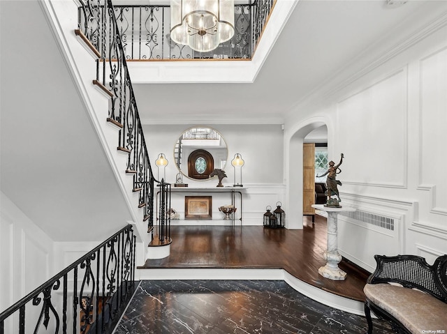 38 Royal Ct, Rockville Centre, NY 11570 - foyer with arched walkways, radiator heating unit, a chandelier, stairway, and a decorative wall