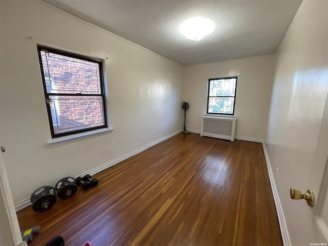 empty room with dark hardwood / wood-style floors and radiator heating unit