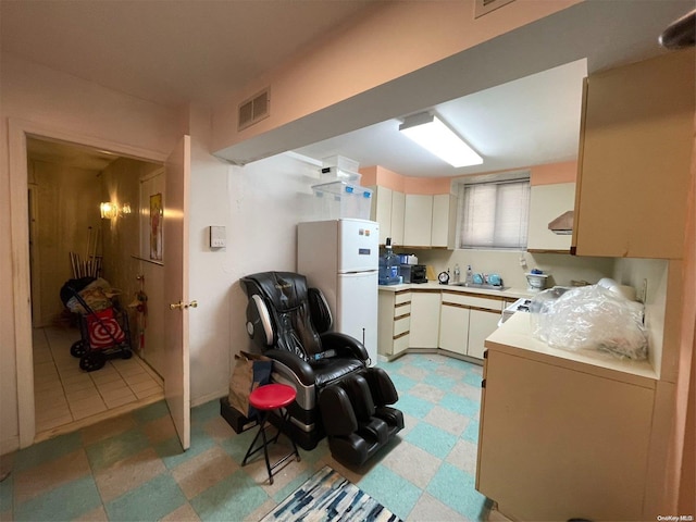 kitchen featuring cream cabinets, white fridge, and sink