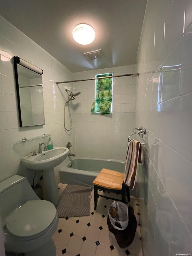 full bathroom featuring sink, tiled shower / bath, tile walls, and toilet