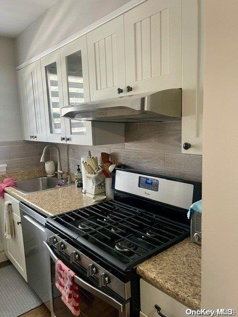 kitchen with white cabinets, sink, decorative backsplash, light stone counters, and stainless steel appliances