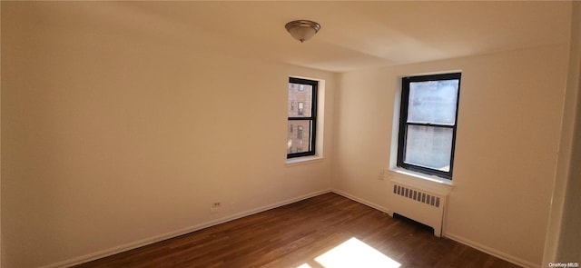 empty room with radiator and dark hardwood / wood-style floors