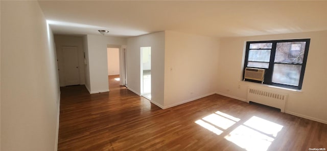 empty room with dark hardwood / wood-style floors, cooling unit, and radiator heating unit