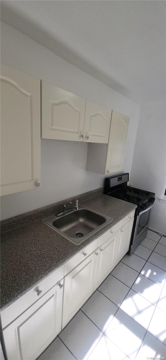 kitchen with light tile patterned floors, white cabinetry, stainless steel electric range oven, and sink