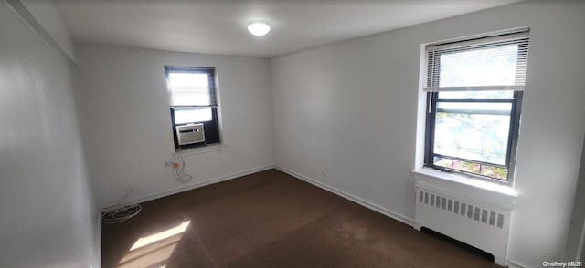 spare room with radiator heating unit, a wealth of natural light, and cooling unit