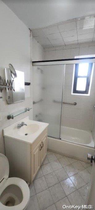 full bathroom with vanity, enclosed tub / shower combo, and toilet