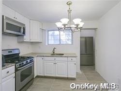 kitchen featuring sink, a notable chandelier, light tile patterned flooring, white cabinetry, and stainless steel appliances