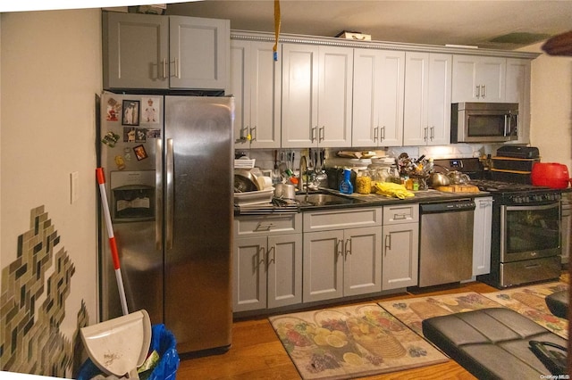 kitchen with gray cabinetry, sink, light wood-type flooring, and stainless steel appliances