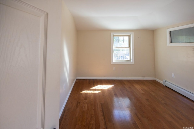 spare room with dark wood-type flooring and a baseboard heating unit