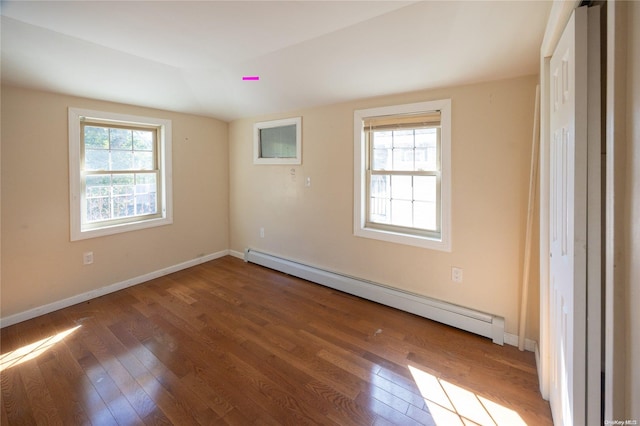 unfurnished bedroom with hardwood / wood-style floors, vaulted ceiling, and a baseboard heating unit