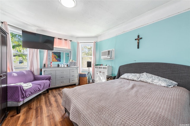 bedroom with a wall mounted AC, dark hardwood / wood-style floors, and multiple windows