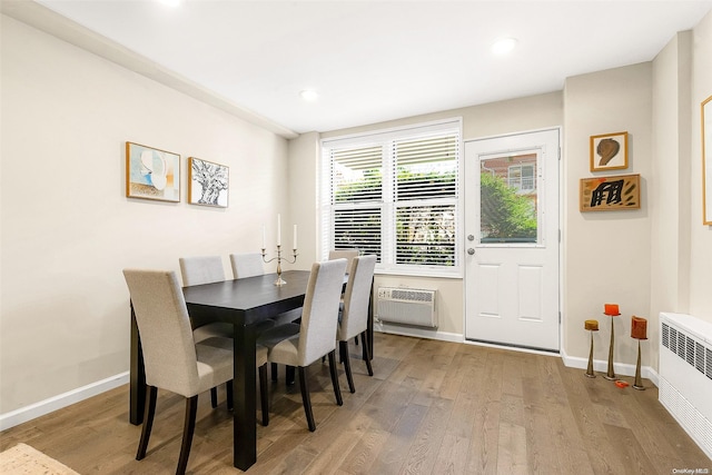 dining room with light hardwood / wood-style floors, a wall unit AC, and radiator