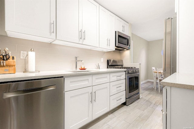 kitchen with white cabinets, sink, appliances with stainless steel finishes, and tasteful backsplash