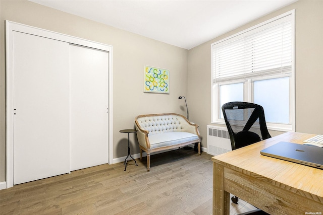 home office with light hardwood / wood-style flooring and radiator heating unit