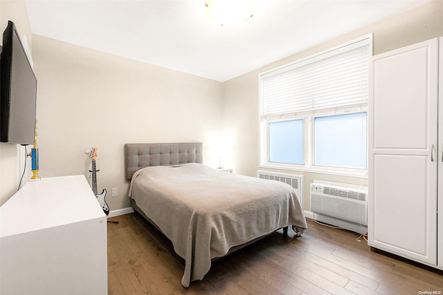 bedroom featuring hardwood / wood-style flooring and a wall mounted AC