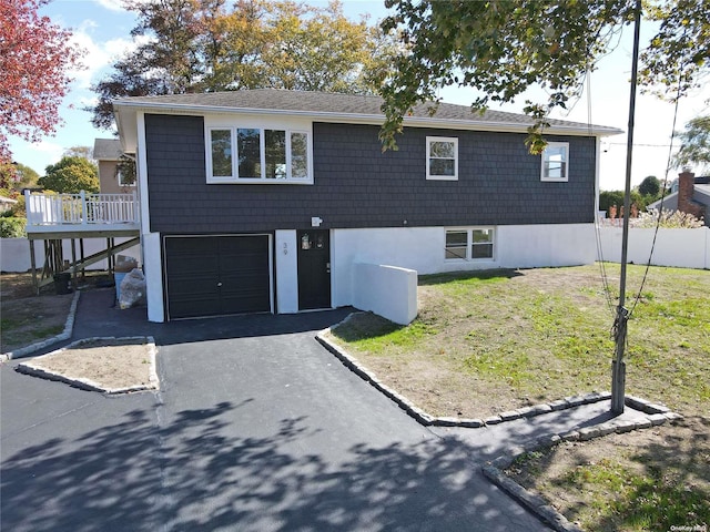 view of front facade with a garage, a wooden deck, and a front yard