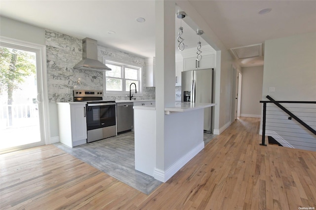 kitchen with pendant lighting, wall chimney exhaust hood, plenty of natural light, and stainless steel appliances