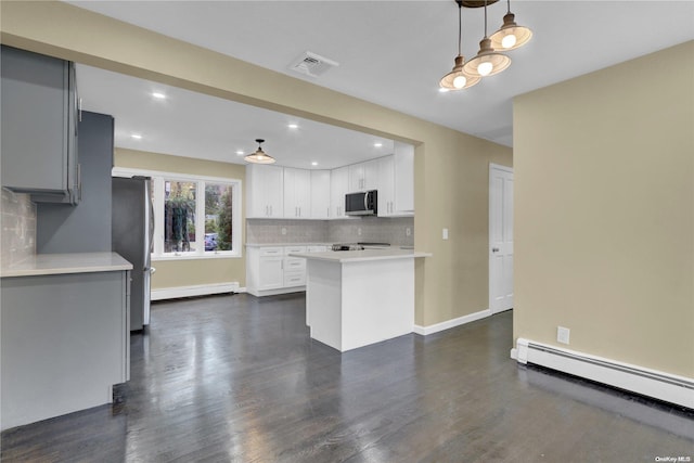 kitchen featuring decorative backsplash, appliances with stainless steel finishes, dark hardwood / wood-style flooring, baseboard heating, and pendant lighting