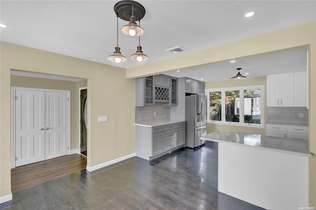 kitchen with stainless steel refrigerator with ice dispenser, backsplash, gray cabinetry, dark hardwood / wood-style floors, and hanging light fixtures