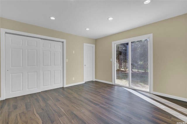 unfurnished bedroom featuring access to exterior, dark hardwood / wood-style flooring, and a closet