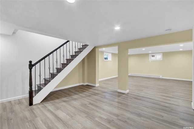 basement featuring light hardwood / wood-style floors and a baseboard heating unit