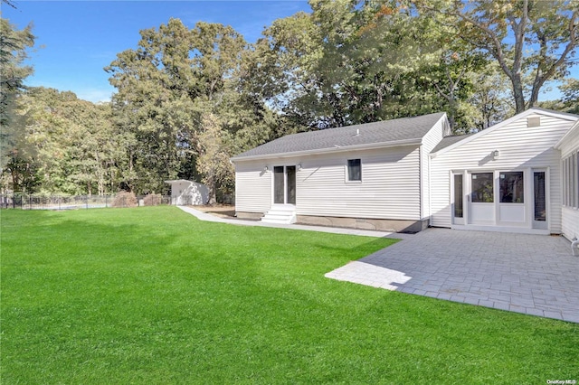 back of house with a yard, a patio, and a storage unit