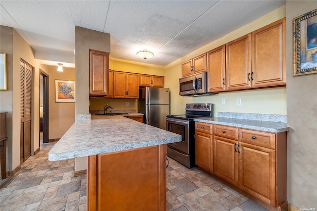 kitchen featuring kitchen peninsula, a textured ceiling, stainless steel appliances, sink, and a breakfast bar area