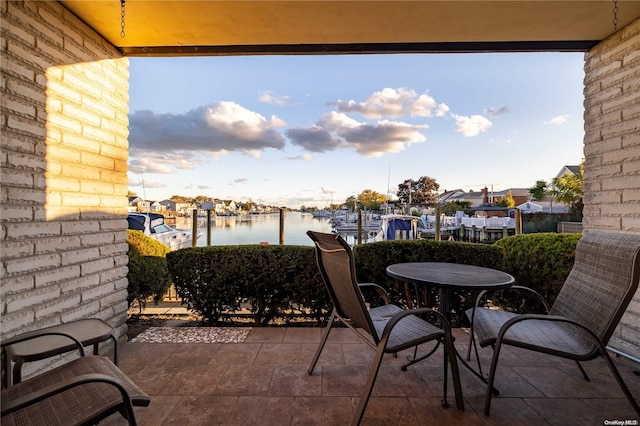 balcony with a patio, a water view, and a dock