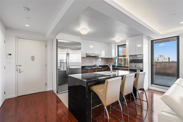 kitchen with white cabinetry, sink, a center island, a kitchen breakfast bar, and appliances with stainless steel finishes