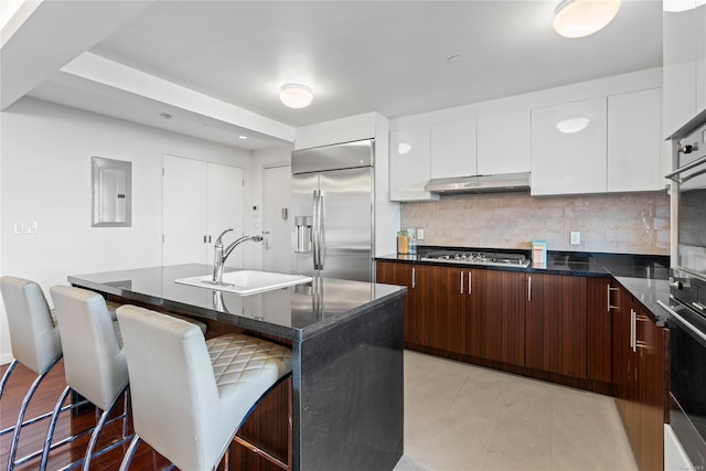 kitchen featuring white cabinets, appliances with stainless steel finishes, a center island with sink, and a kitchen breakfast bar