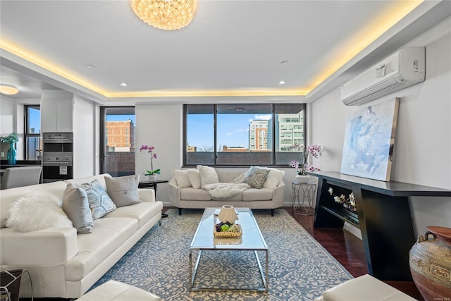 living room with a raised ceiling, a wall mounted AC, a chandelier, and dark hardwood / wood-style floors