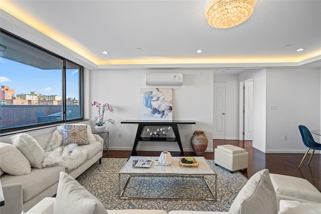 living room featuring an AC wall unit, a raised ceiling, dark hardwood / wood-style floors, and a notable chandelier