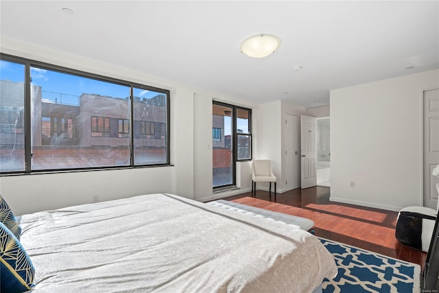 bedroom featuring ensuite bathroom and dark hardwood / wood-style flooring