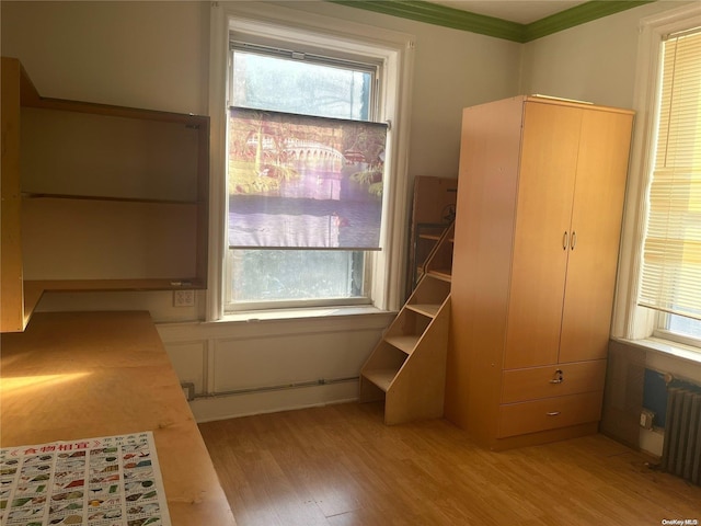 bedroom with radiator heating unit, light hardwood / wood-style floors, and crown molding