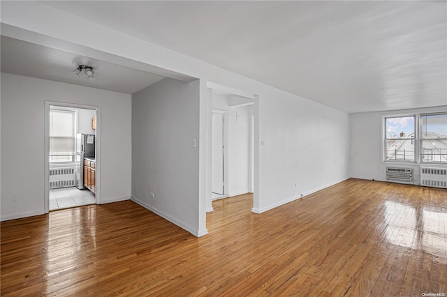 unfurnished living room featuring radiator heating unit and light hardwood / wood-style floors