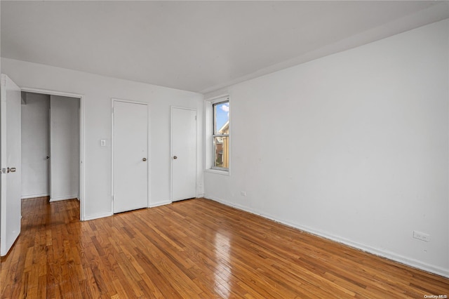 unfurnished bedroom featuring multiple closets and hardwood / wood-style flooring