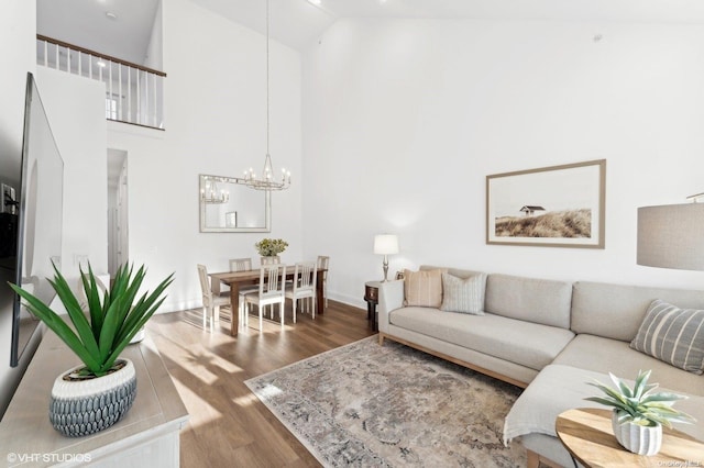 living room featuring dark hardwood / wood-style flooring, high vaulted ceiling, and an inviting chandelier