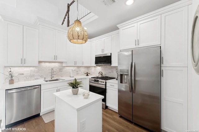 kitchen with hanging light fixtures, sink, appliances with stainless steel finishes, and dark wood-type flooring