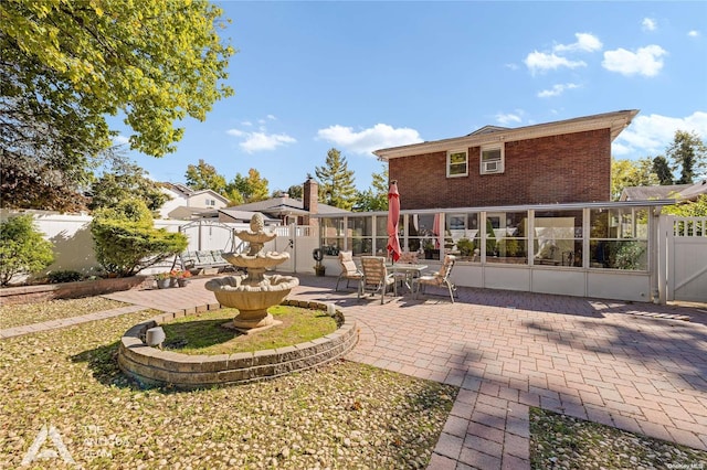 rear view of property featuring a sunroom and a patio area