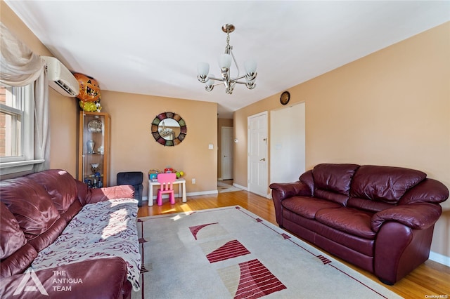 living room with a wall mounted air conditioner, light hardwood / wood-style floors, and an inviting chandelier