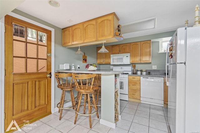 kitchen featuring a kitchen bar, white appliances, light stone counters, and light tile patterned flooring