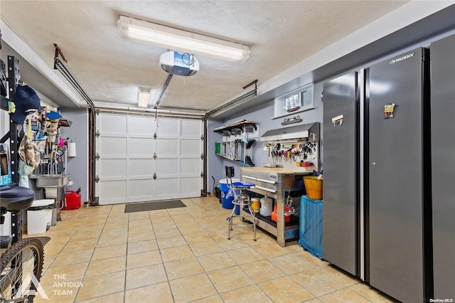 garage with a garage door opener, a workshop area, and stainless steel refrigerator