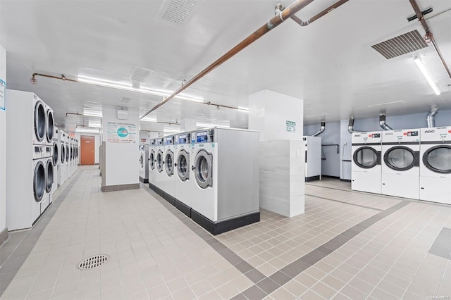 laundry room with light tile patterned floors, stacked washer and dryer, and washer and clothes dryer