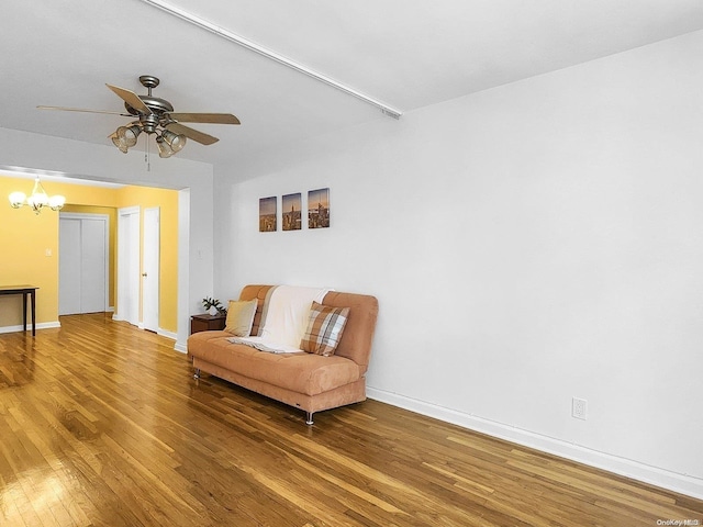 sitting room featuring hardwood / wood-style floors and ceiling fan with notable chandelier