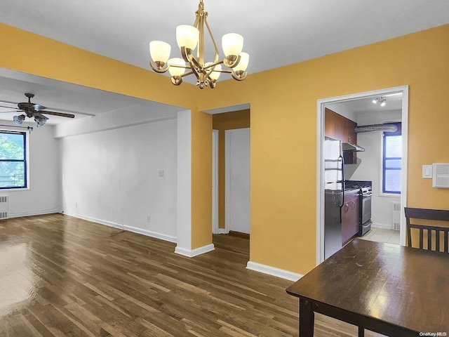 unfurnished dining area featuring ceiling fan with notable chandelier, dark hardwood / wood-style floors, and radiator